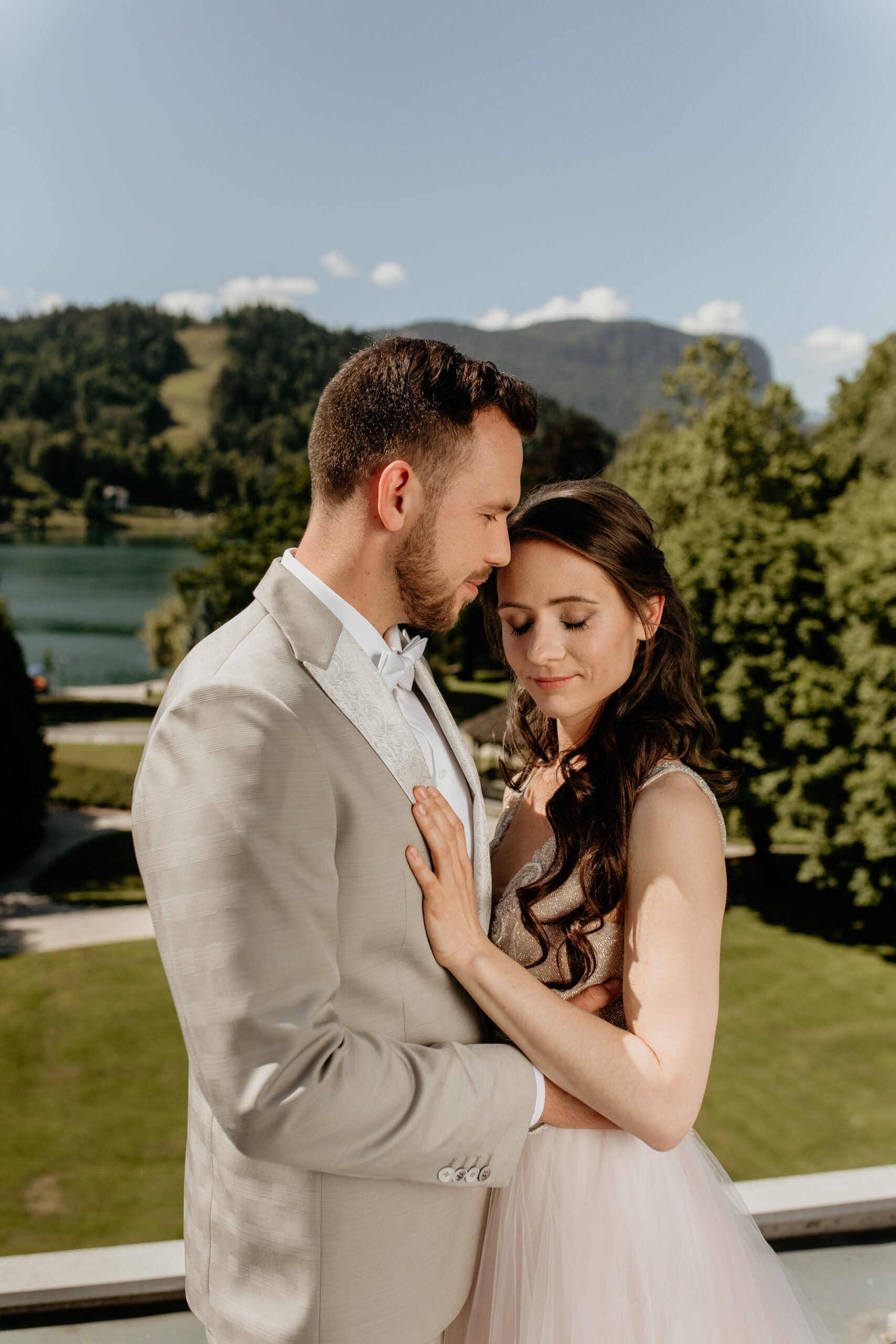 Wedding couple embracing on the terrace of Bled Rose Hotel with the lake behind