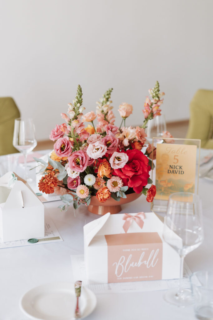Floral centrepiece with a table number in coral tones