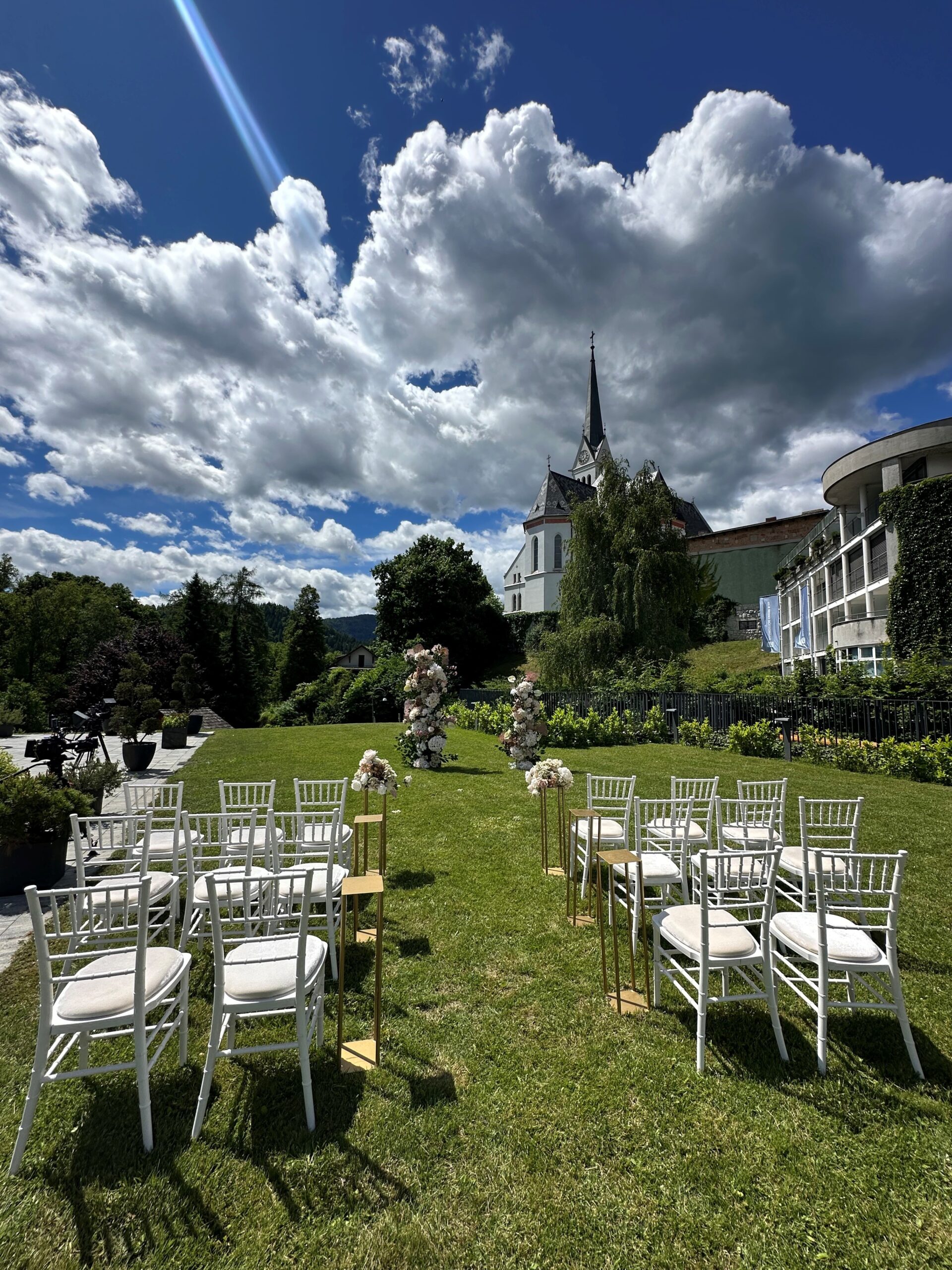 White chiavari chairs and floral arch set for a garden wedding ceremony at Bled Rose Hotel