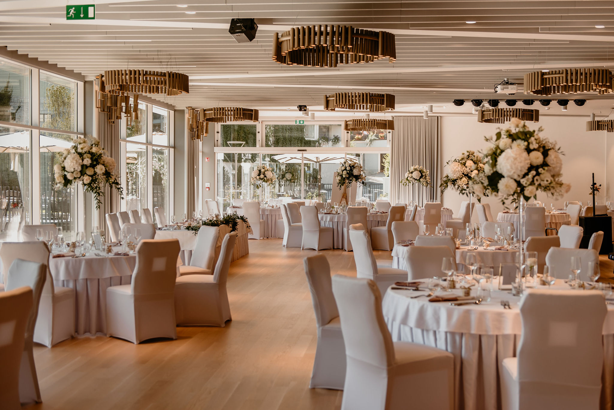 Rose hall at Bled Rose Hotel fully set for a wedding dinner with round tables and candles